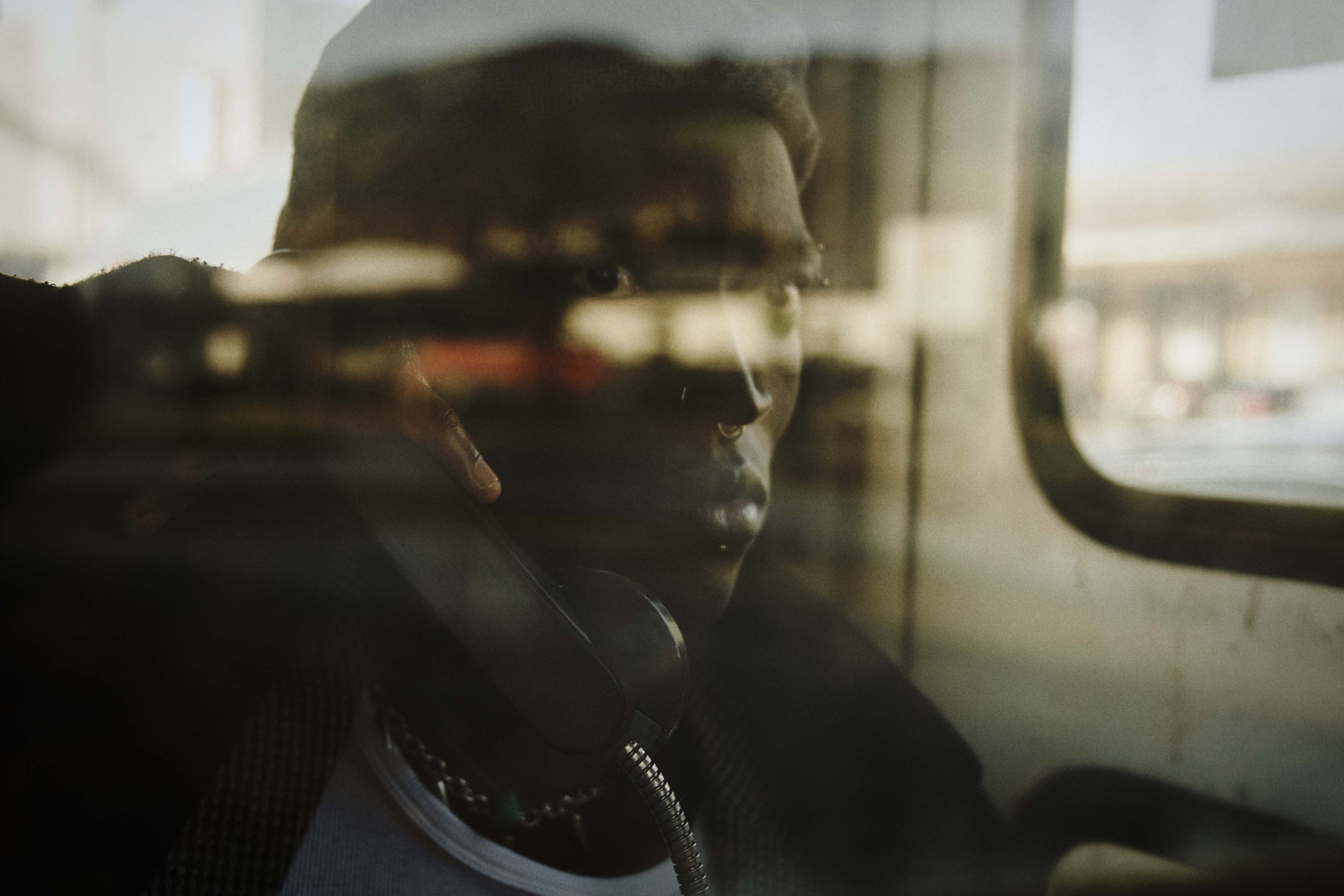 cinematisches Porträt von Kelvin Addai in einer Telefonzelle, im Vintage-Style fotografiert