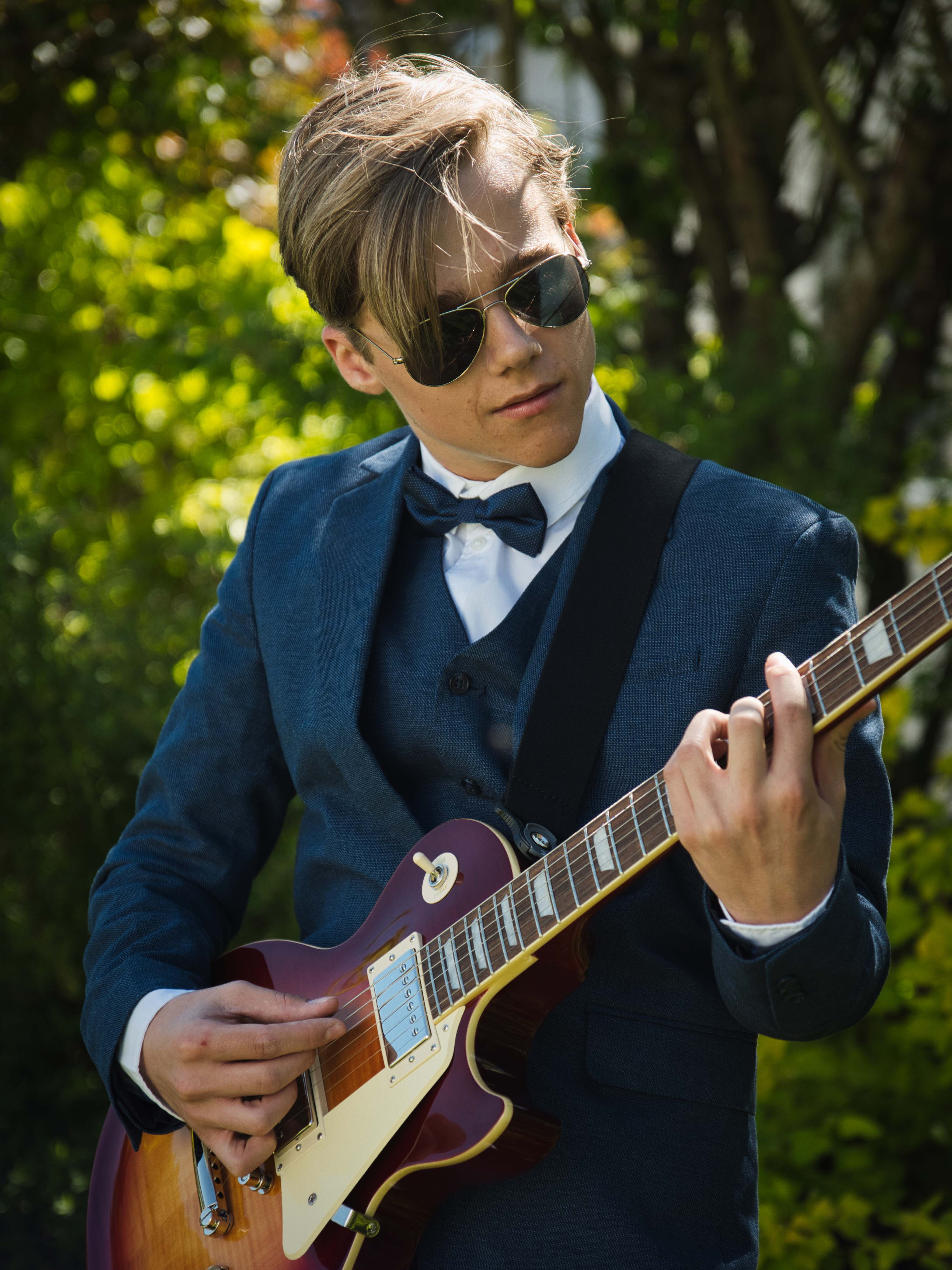 Outdoor Porträt von Tobias Lorenz im Anzug mit Sonnenbrille, der eine E-Gitarre spielt