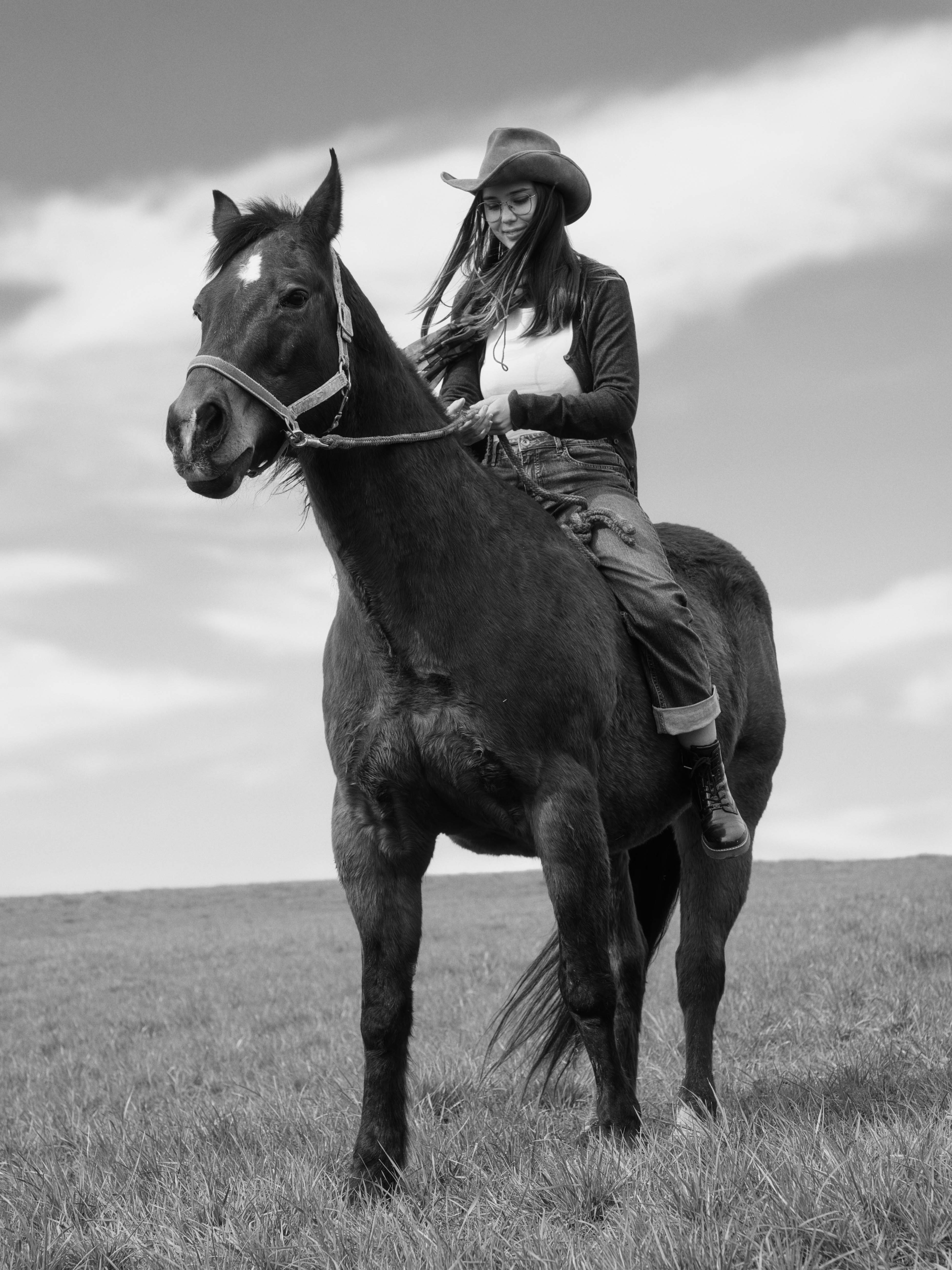 Lena Lorenz sitzt auf einem schwarzen Pferd, Porträt in Schwarzweiß