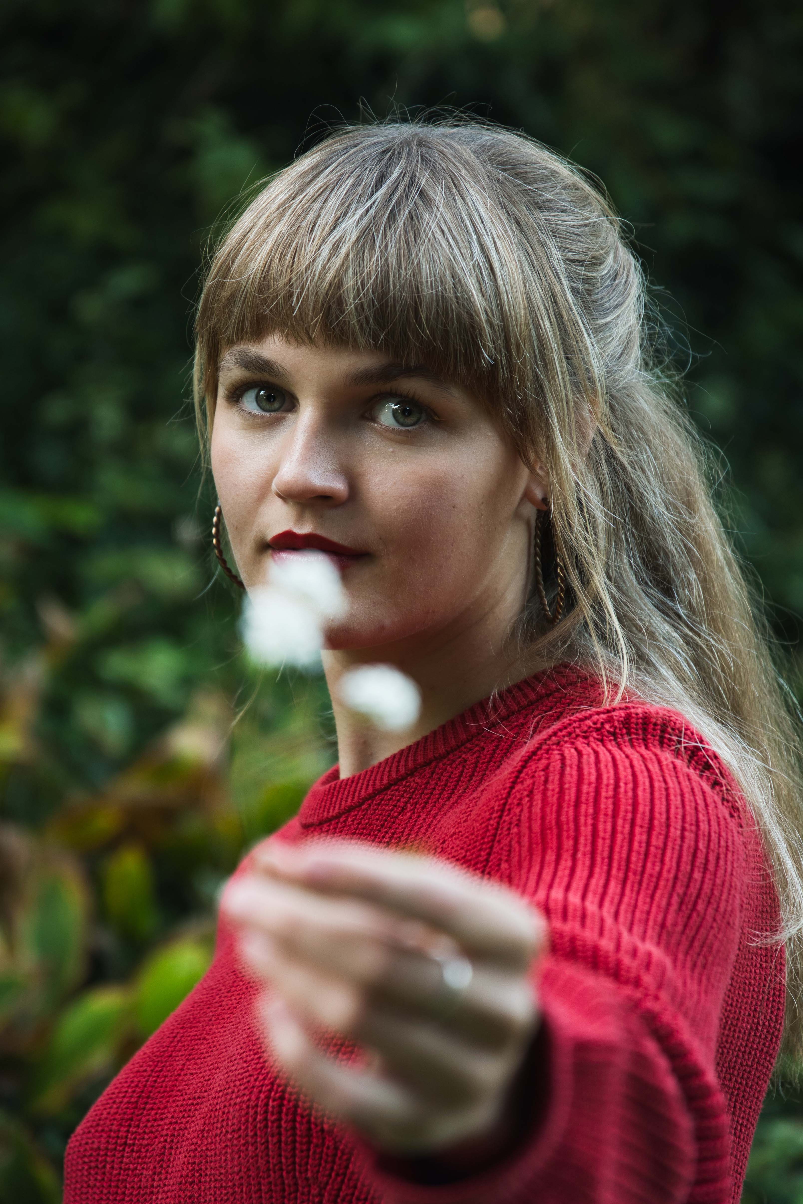 natürliches Portrait einer jungen Frau, die eine weiße Blume vor sich hält