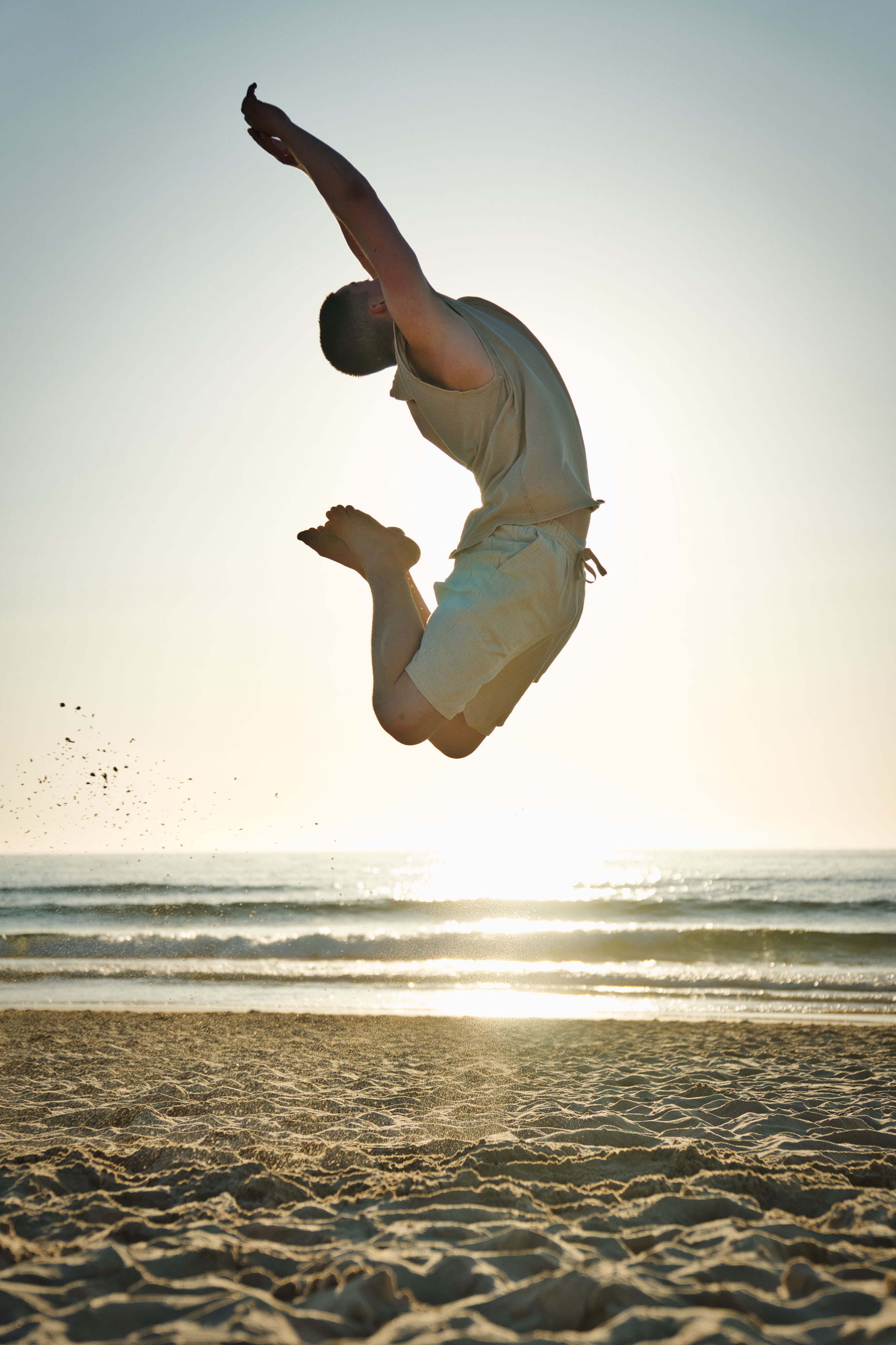 Lorenz Dietrich macht einen akrobatischen Sprung am Strand bei Sonnenuntergang